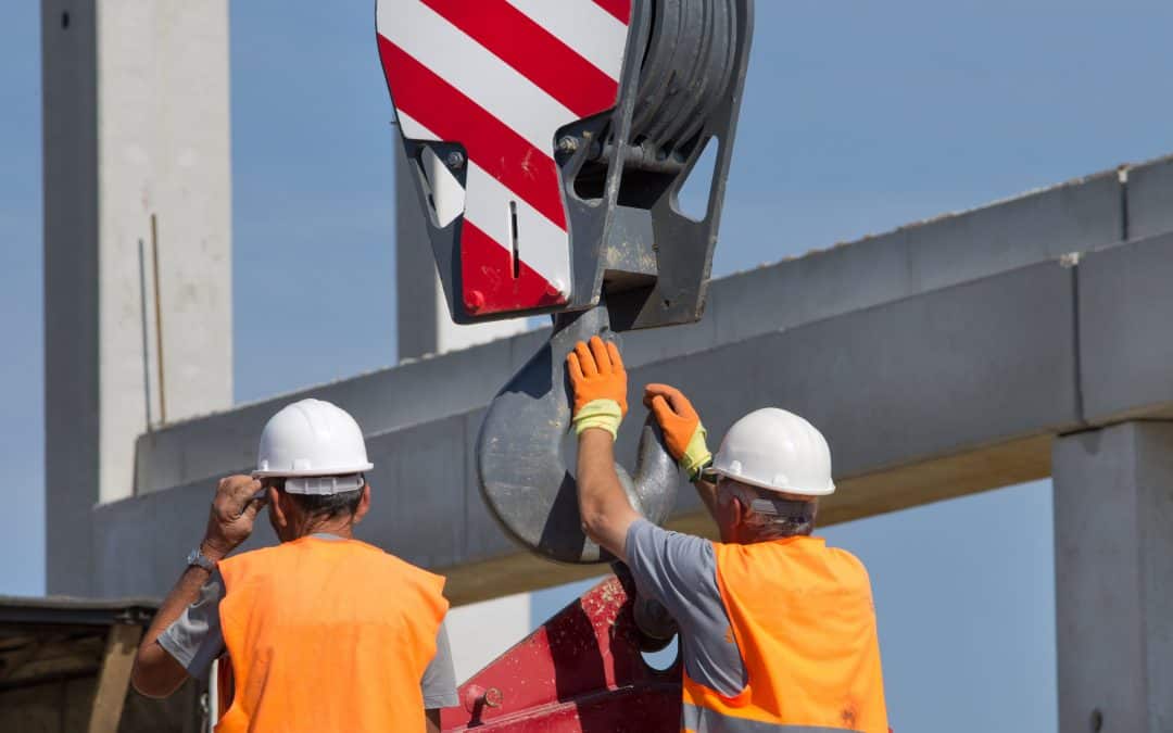 Two men in high-vis vests using lifting equipment